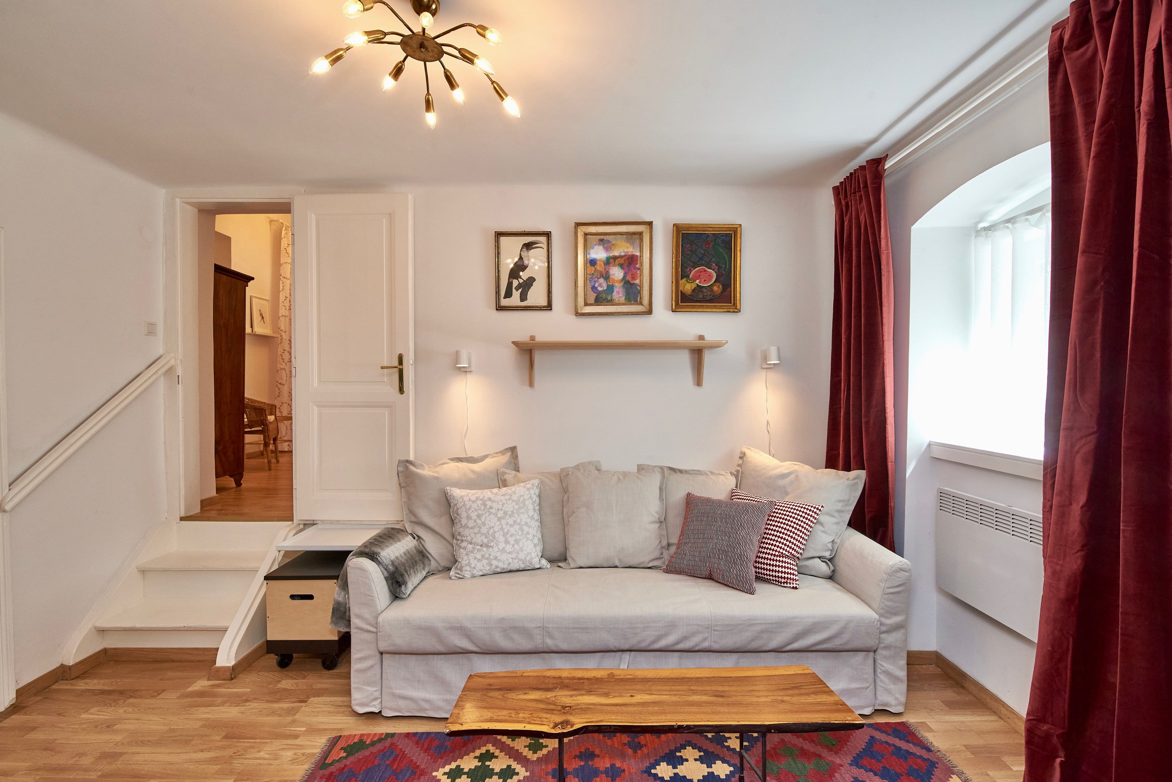 Gemütliches Wohnzimmer mit Sofa, Holztisch, Teppich und Wandbildern.