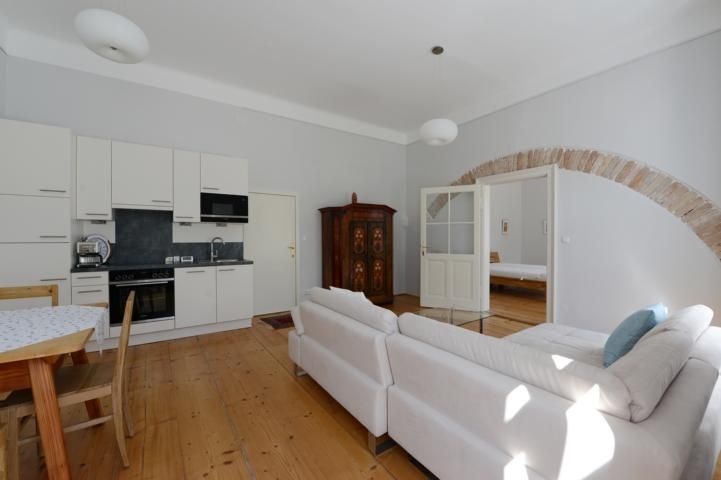 Helles Wohnzimmer mit Küche, Sofa und Esstisch.