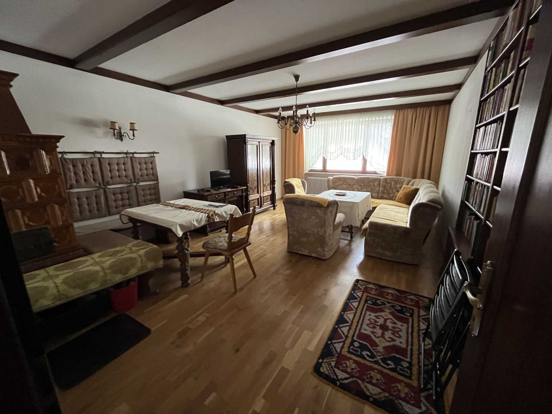 Wohnzimmer mit Holzboden, Sofa, Tisch, Schrank und Kamin.