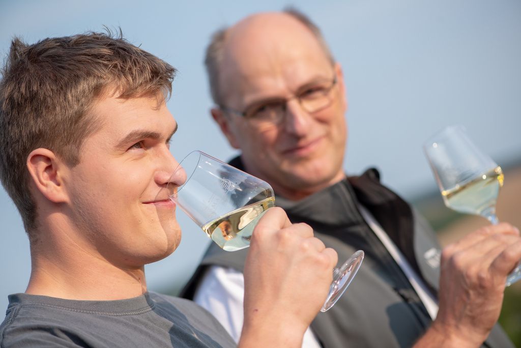 Zwei Männer genießen Weißwein im Freien.