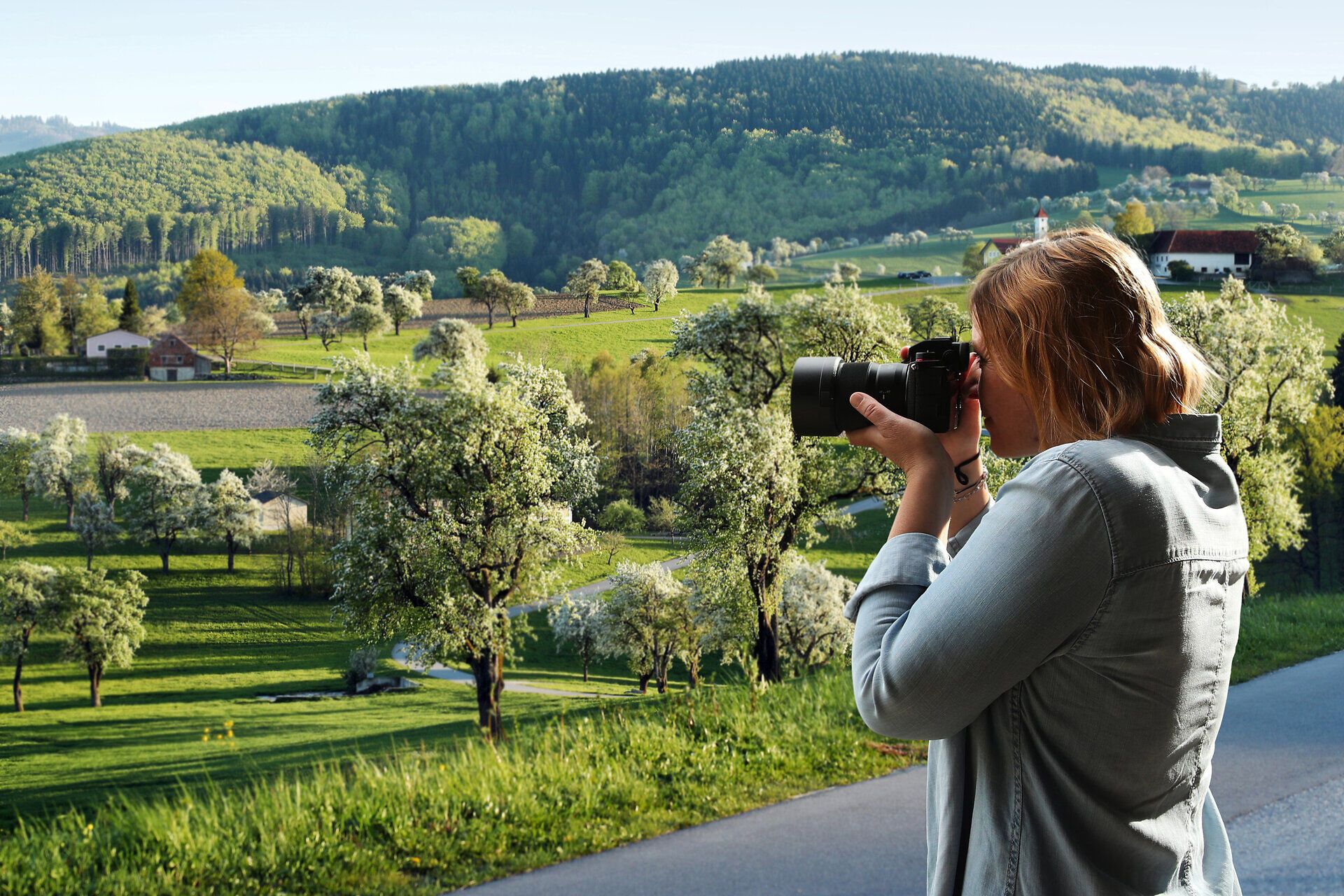 Frau fotografiert blühende Landschaft mit Kamera.