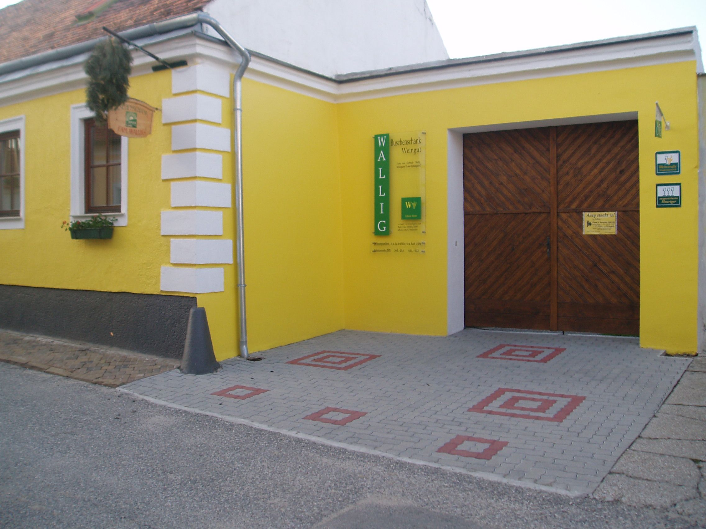 Gelbes Gebäude mit Holztor und Schild 'Wallig'.