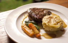 Ein Teller mit einem St&uuml;ck Fleisch, Gem&uuml;se und einer Kartoffelbeilage.