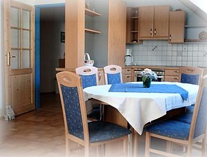 Essbereich einer Ferienwohnung mit Holzm&ouml;beln und blauer Tischdecke.