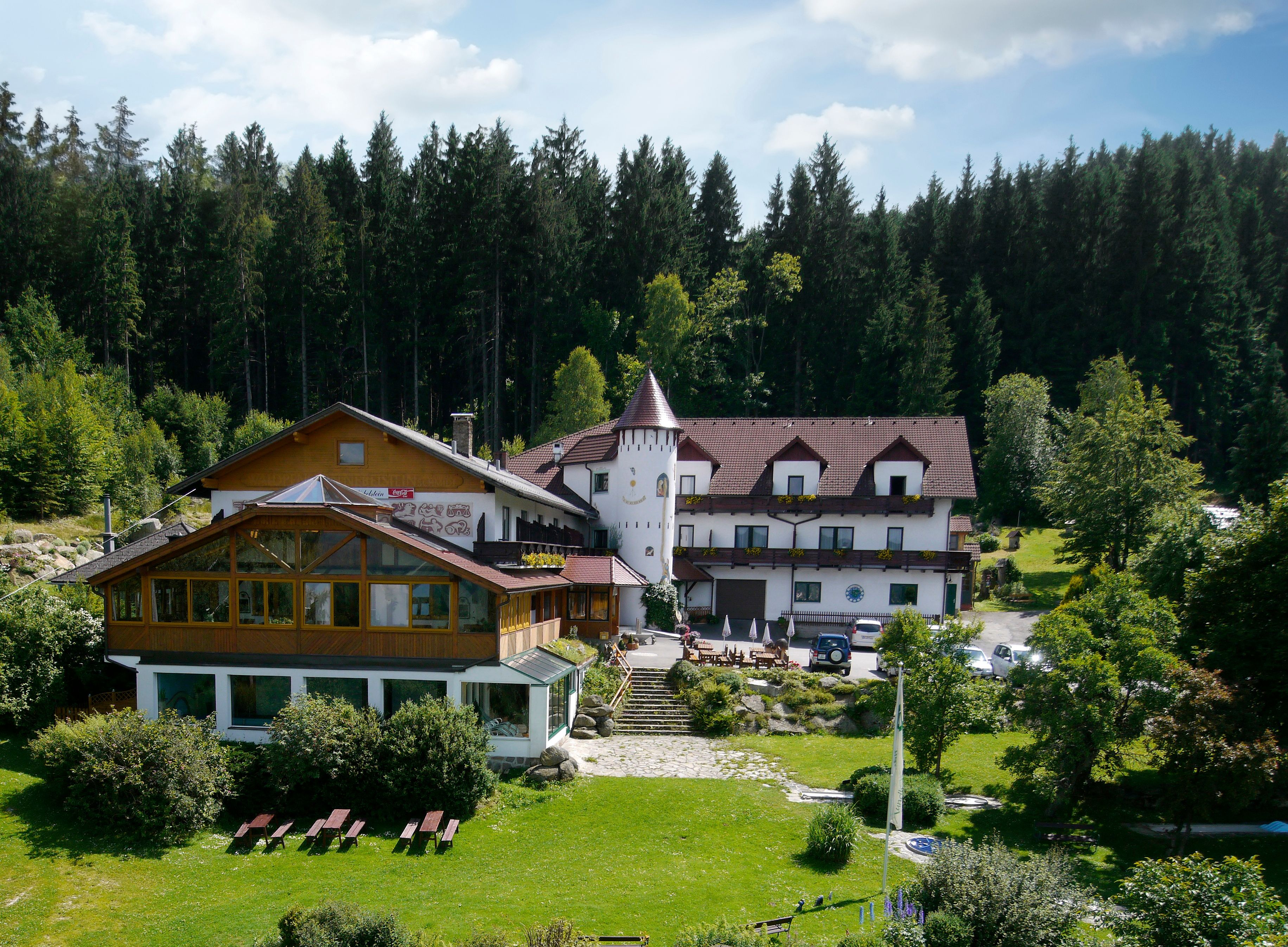 Ein Hotel im Wald mit einem Turm und Garten.