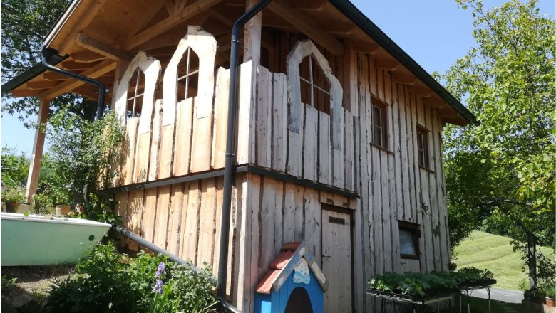 Holzhaus im Naturgarten mit Pflanzen.