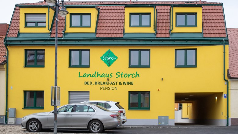 Gelbes Geb&auml;ude mit der Aufschrift 'Landhaus Storch', davor geparkte Autos.