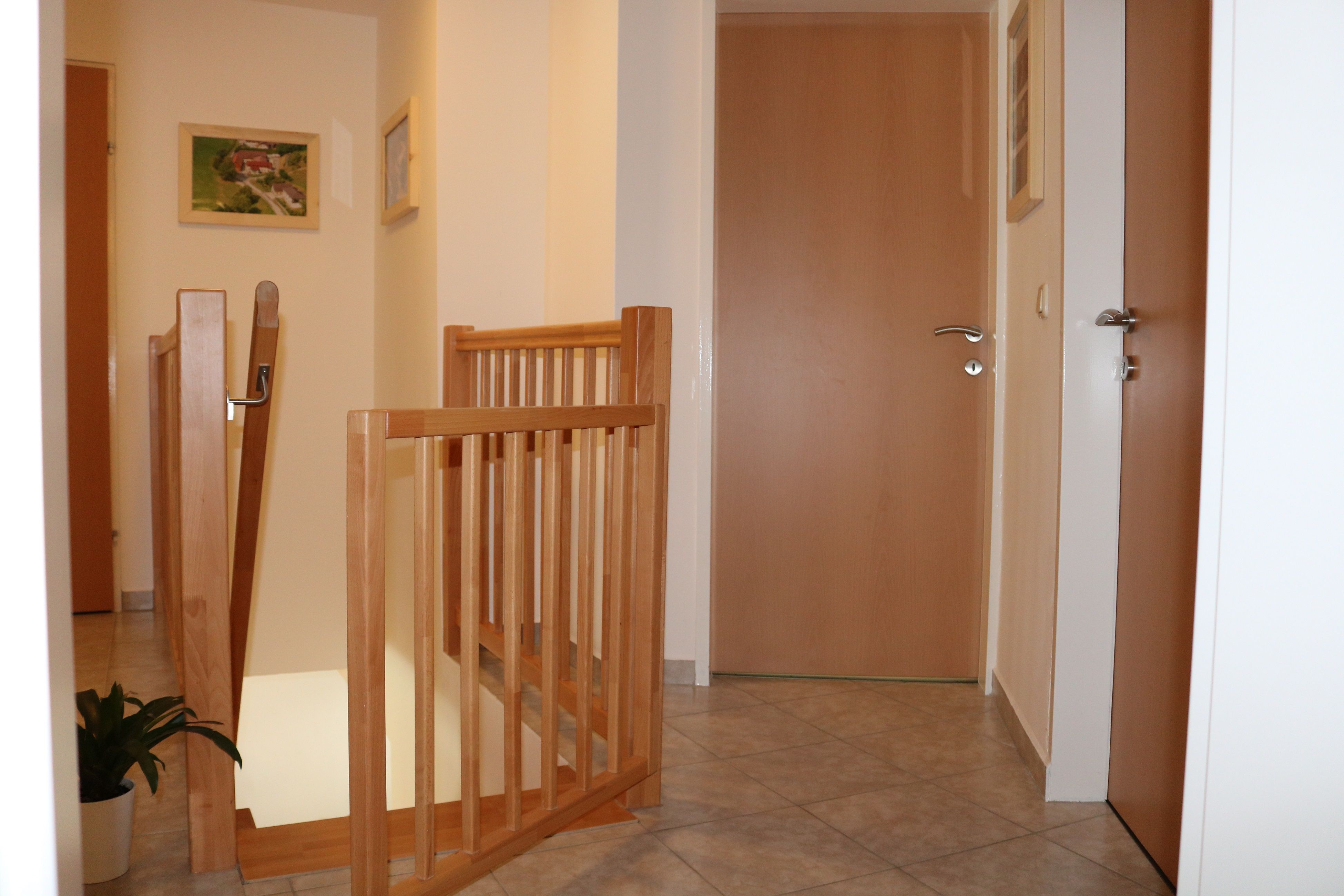 Innenansicht eines Flurs mit Holztüren und Treppengeländer.