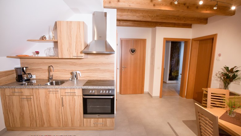 Moderne K&uuml;che mit Holzdekor, Esstisch und Blumen.