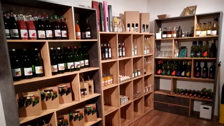 Regale mit verschiedenen Flaschen und Produkten in einem Hofladen.