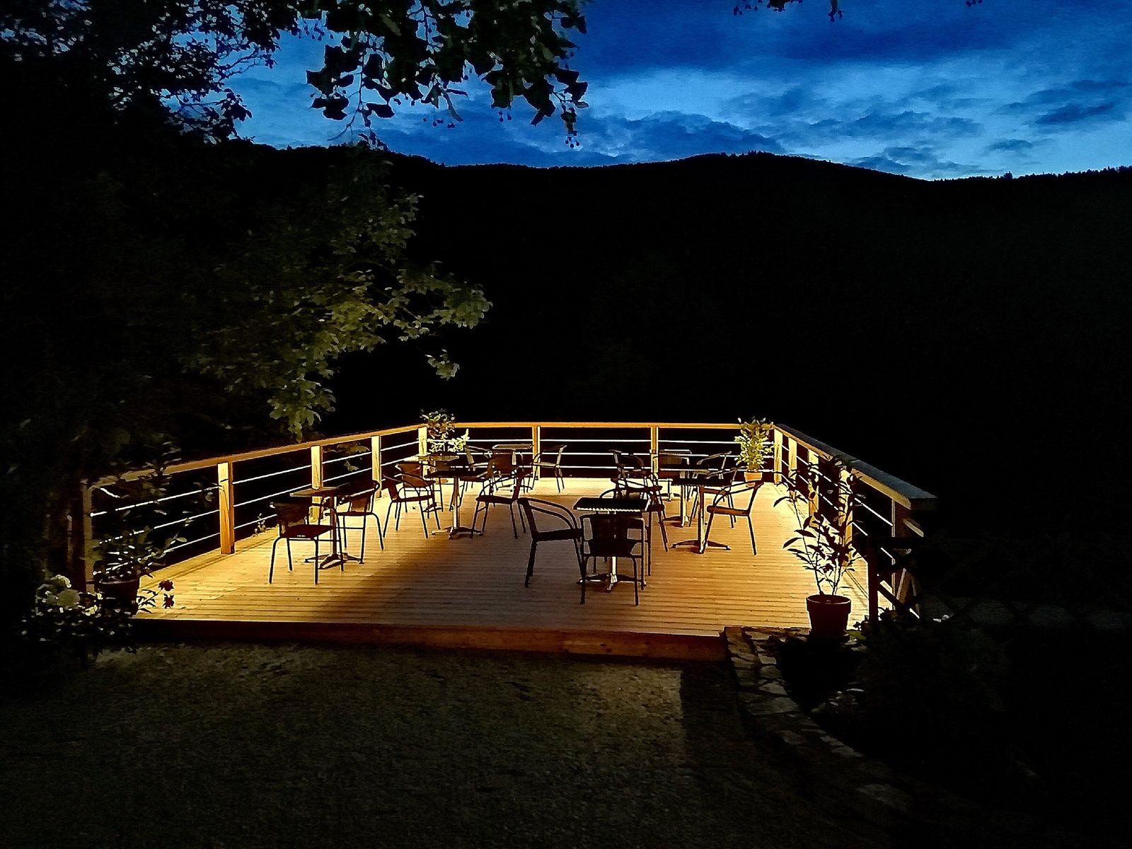 Beleuchtete Terrasse mit Stühlen und Tischen bei Nacht.