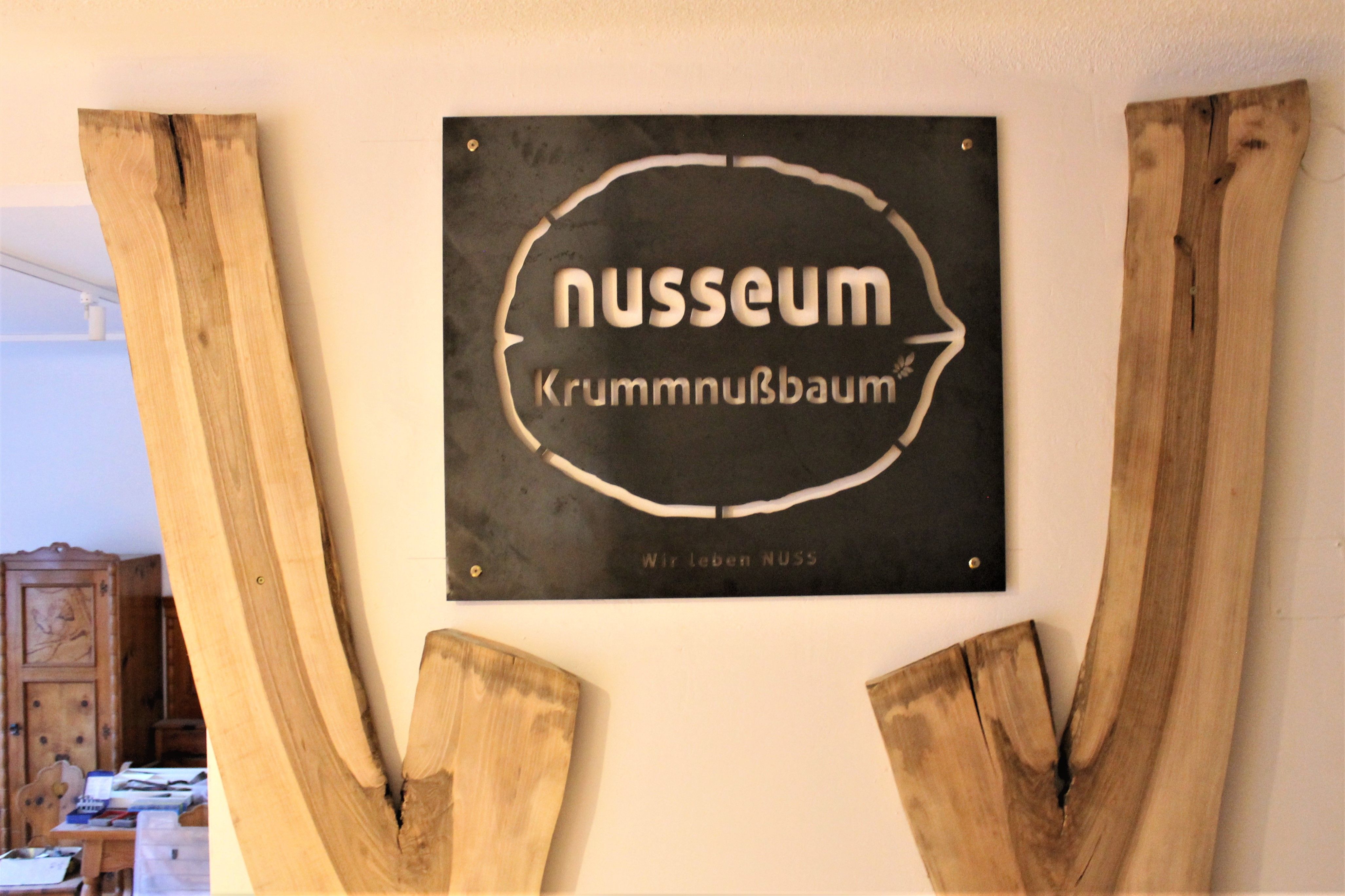 Schild des Nusseum Krummnußbaum mit Holzdekoration.