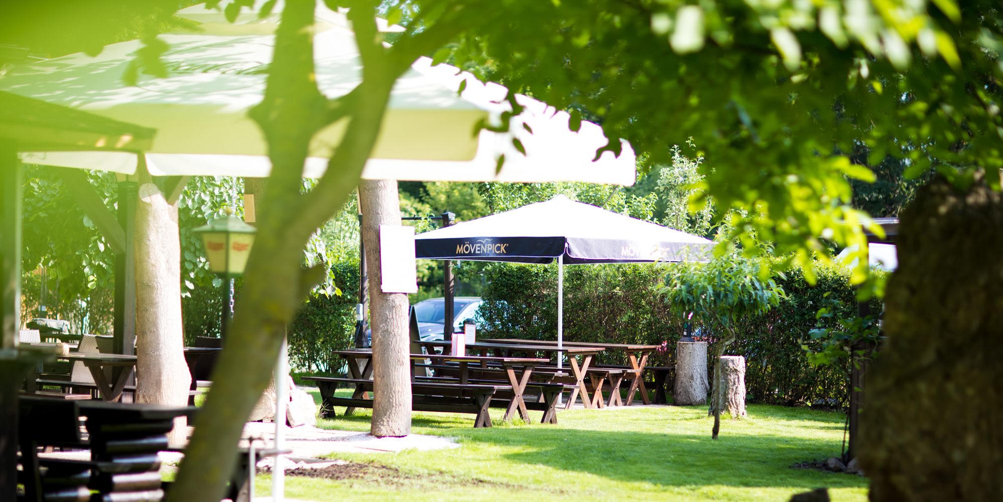 Einladender Gastgarten mit schattenspendenden Schirmen und Heurigengarnituren 