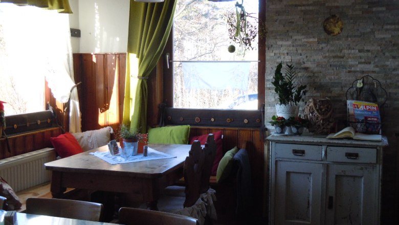 Gem&uuml;tliche Ecke in einem Raum mit Holztisch, Kissen und Pflanzen.