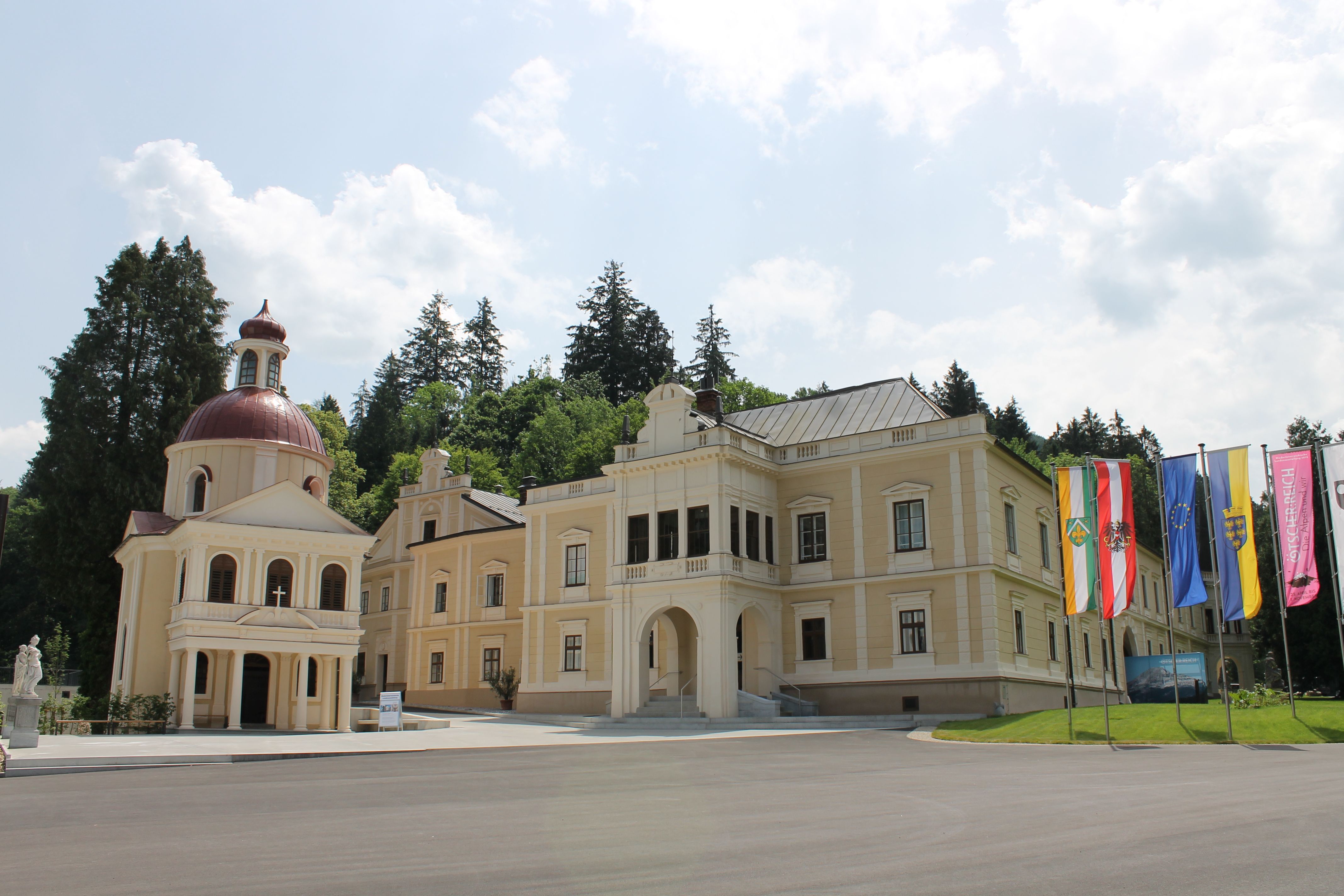 Schloss Neubruck mit Kapelle und Fahnen im Vordergrund.