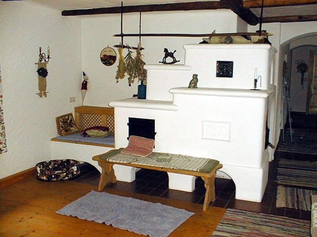 Gemütlicher Raum mit weißem Kachelofen und Holzbalken.