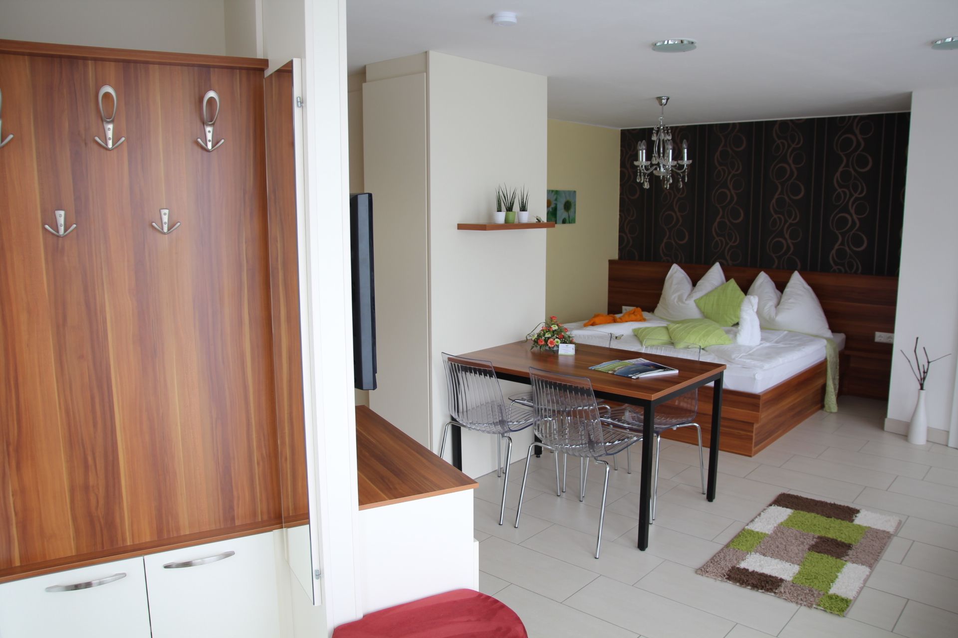 Modernes Appartement mit Holzmöbeln, Esstisch, Bett und dekorativen Elementen.