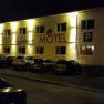 Nachtaufnahme eines beleuchteten Motels mit dem Schriftzug 'Hainburg Motel' und geparkten Autos davor.