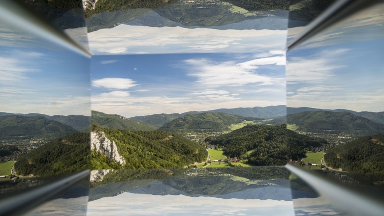 Spiegelung einer Berglandschaft mit blauem Himmel und Wolken.