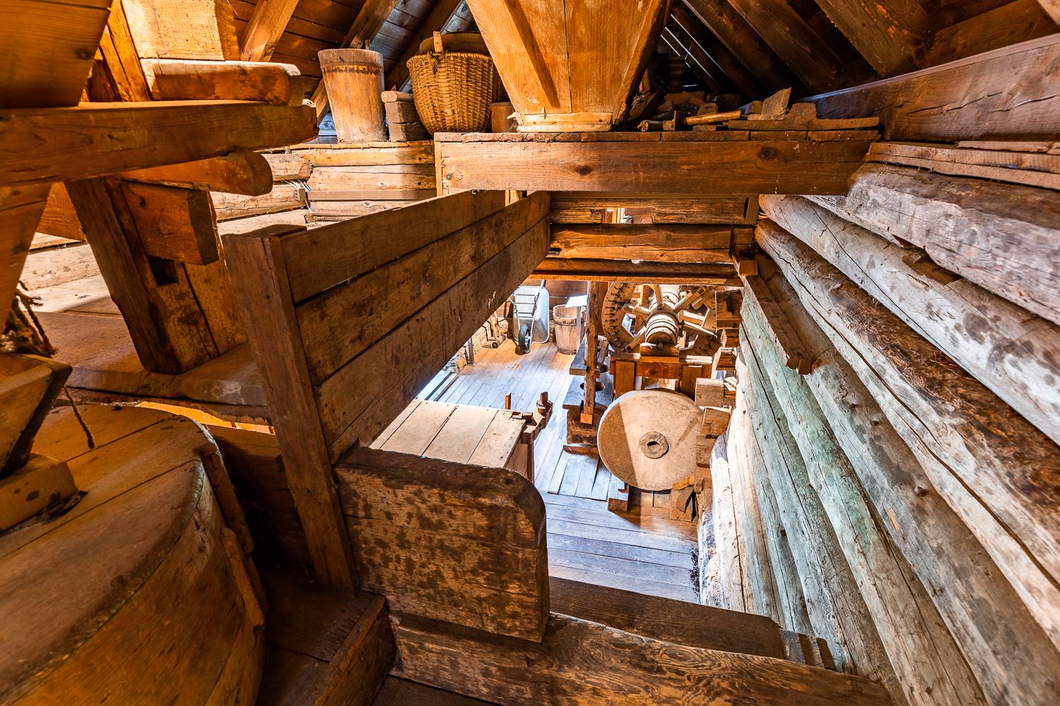Innenansicht einer alten Mühle mit Holzkonstruktionen und Mühlstein.