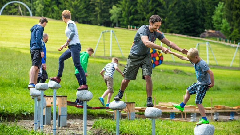Menschen balancieren auf Steinen im Motorikpark.