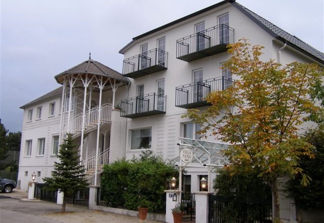 Eingang, © Villa Nina Ein mehrstöckiges Gebäude mit Balkonen und einem Eingang mit Säulen.