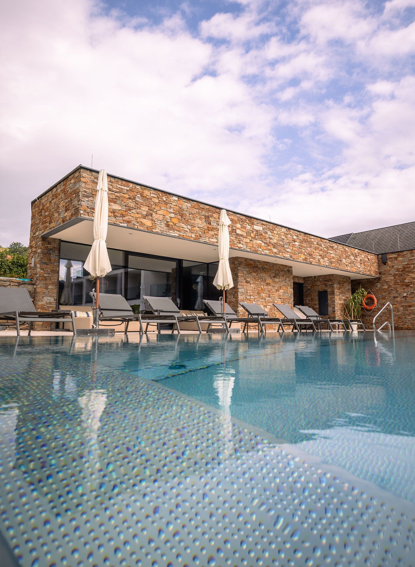 Außenansicht eines modernen Hotels mit Pool und Liegestühlen.