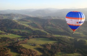 Heißluftballon über grüner Hügellandschaft im Traisental.