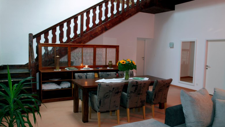 Essbereich in einem Loft mit Holztisch, St&uuml;hlen, Treppe und Pflanzen.