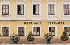 Fassade eines gelben Gasthauses mit der Aufschrift 'Gasthaus Ellinger'.