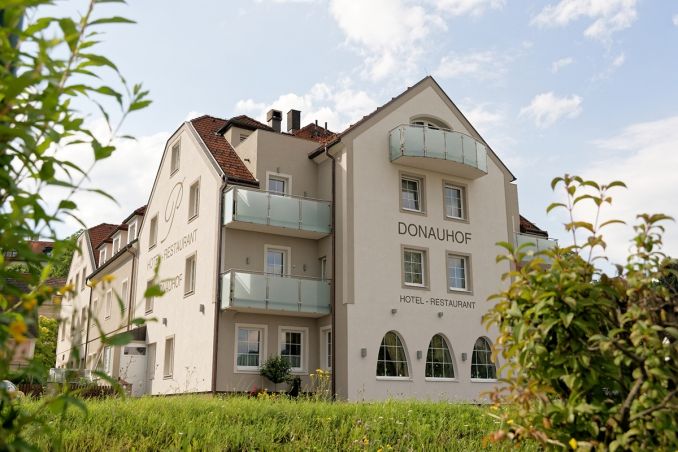 Außenansicht des Hotel Restaurant Donauhof mit Balkonen und Garten.