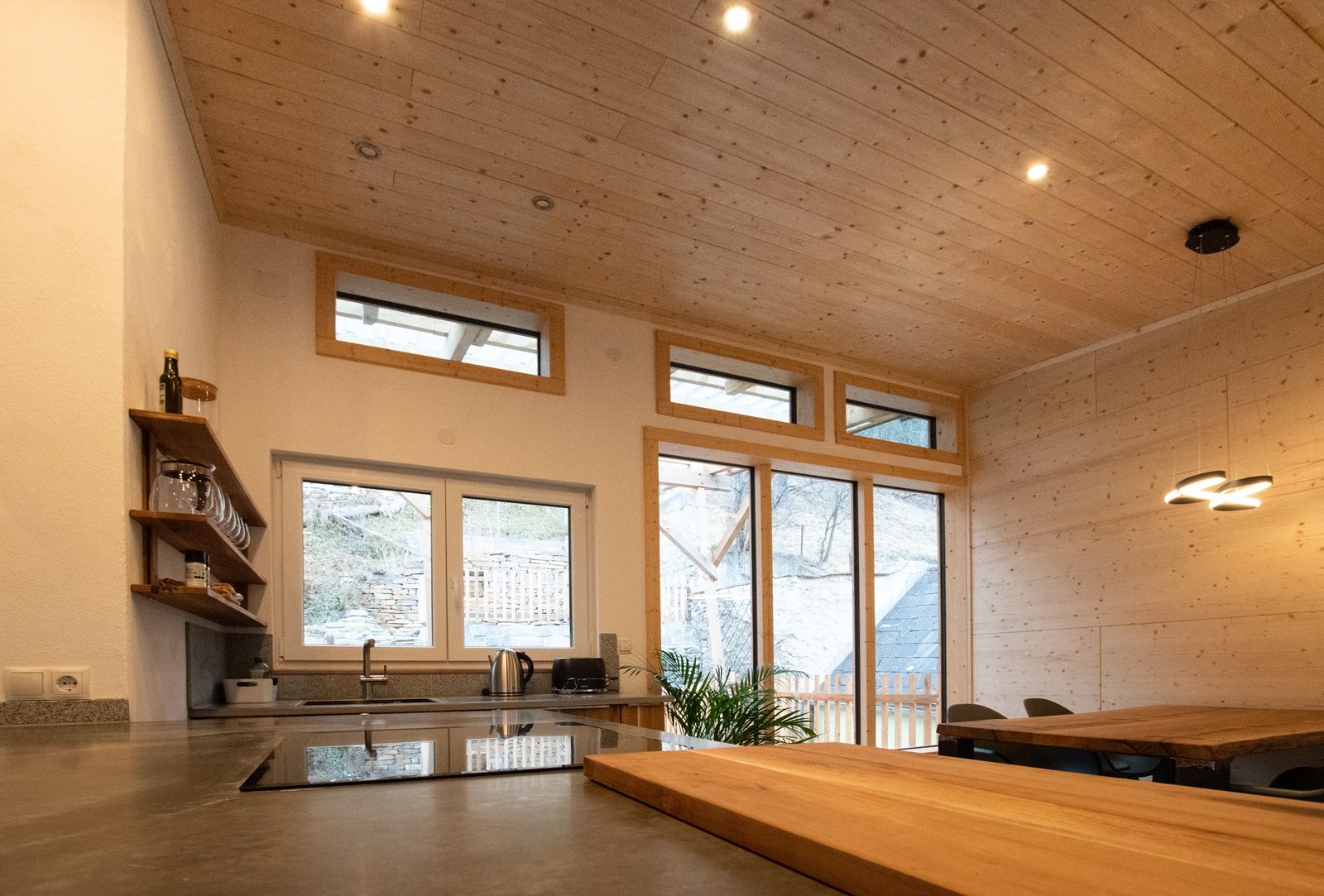 Moderne Küche mit Holzdecke und großen Fenstern.
