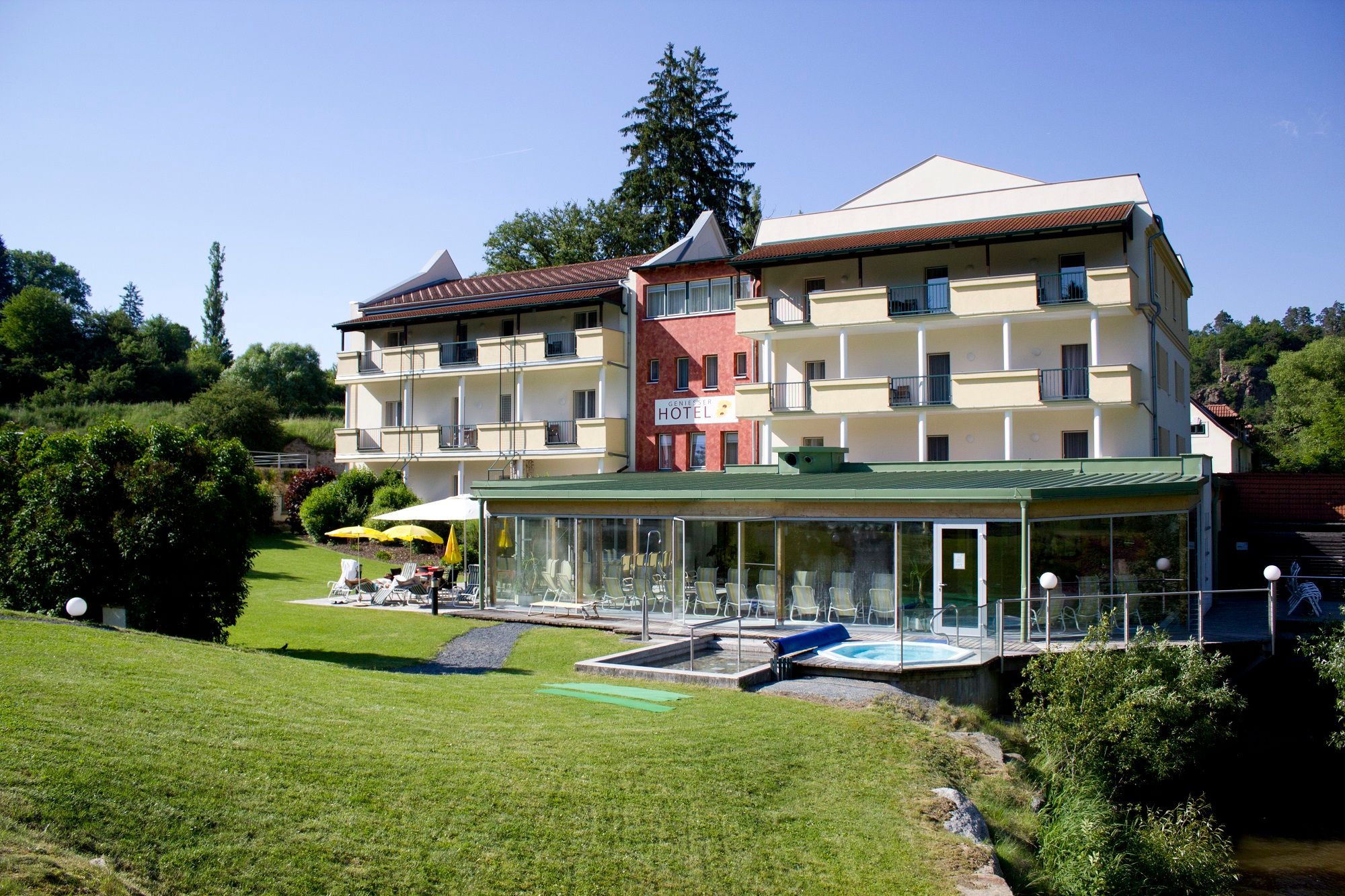 Außenansicht eines Hotels mit Garten und Poolbereich.