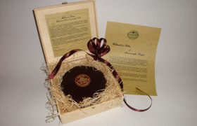 Eine dekorative Schachtel mit einer runden Schokolade und einem Informationsblatt.