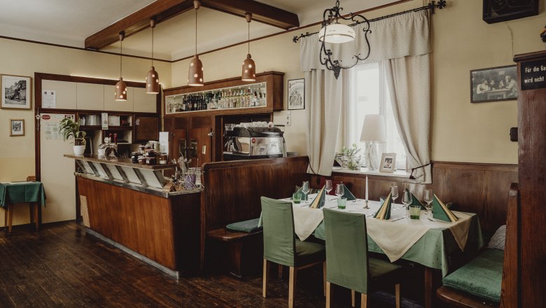 Gem&uuml;tliches Caf&eacute; mit Holzm&ouml;beln, gedecktem Tisch und Barbereich.