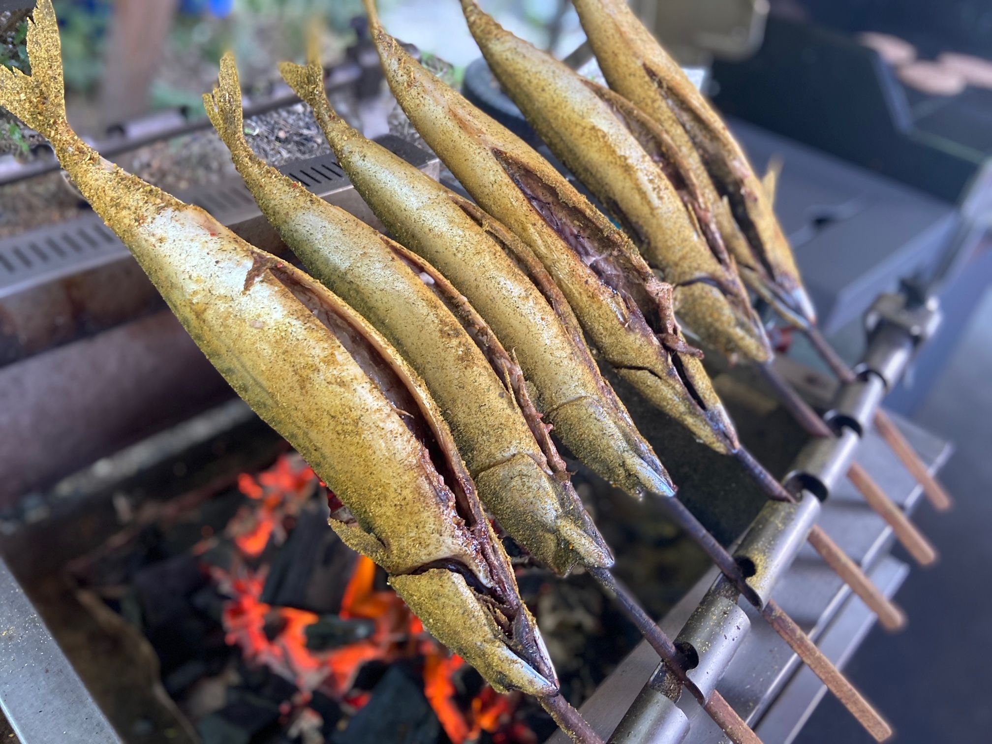 Steckerlfisch auf einem Grill über glühender Kohle.