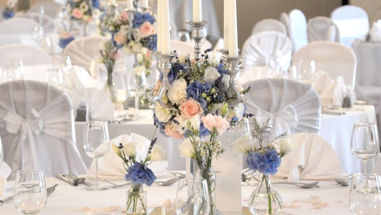 Elegante Tischdekoration mit Blumen und Kerzen in einem Festsaal.