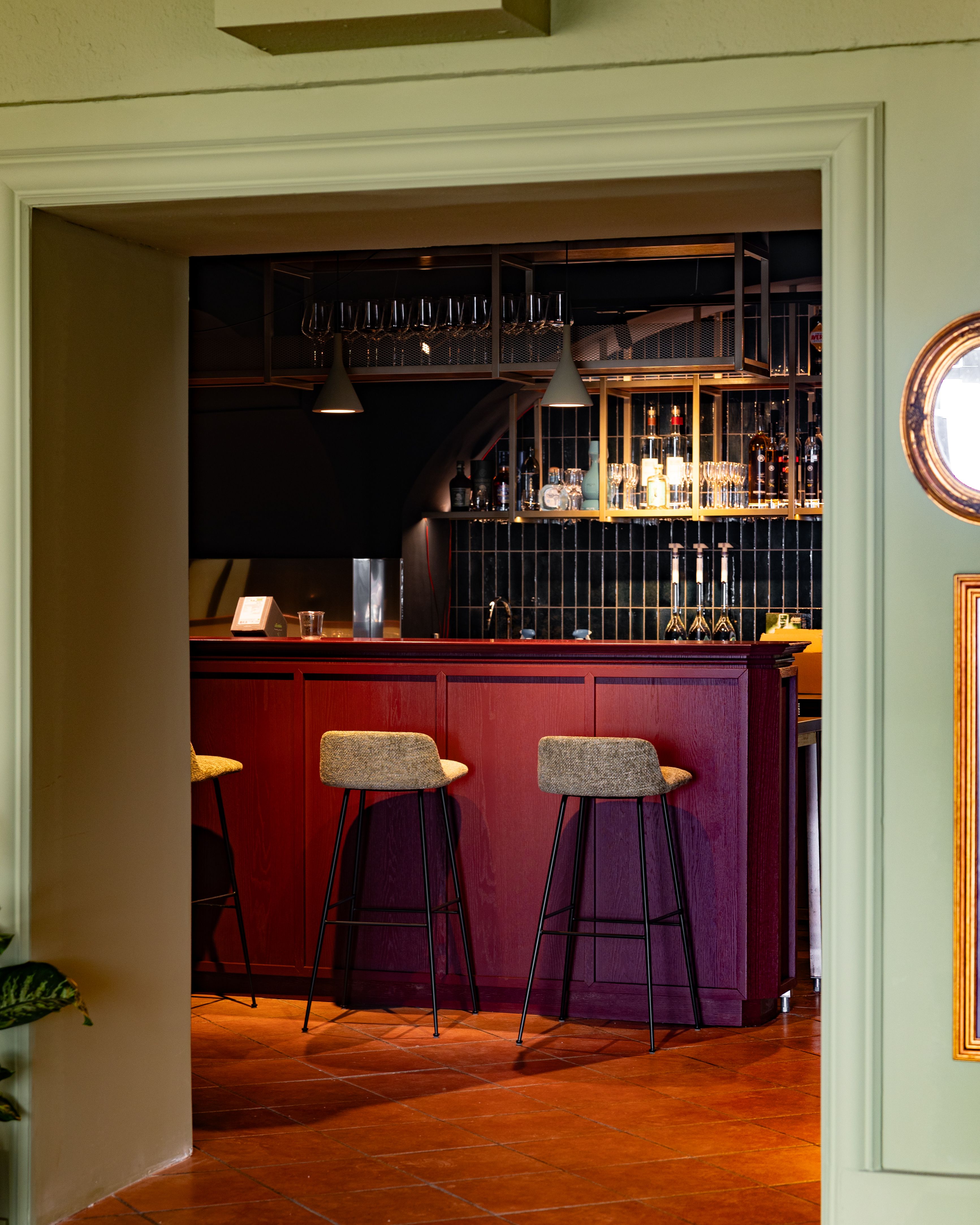 Elegante Bar mit roten Holzmöbeln und hohen Stühlen.