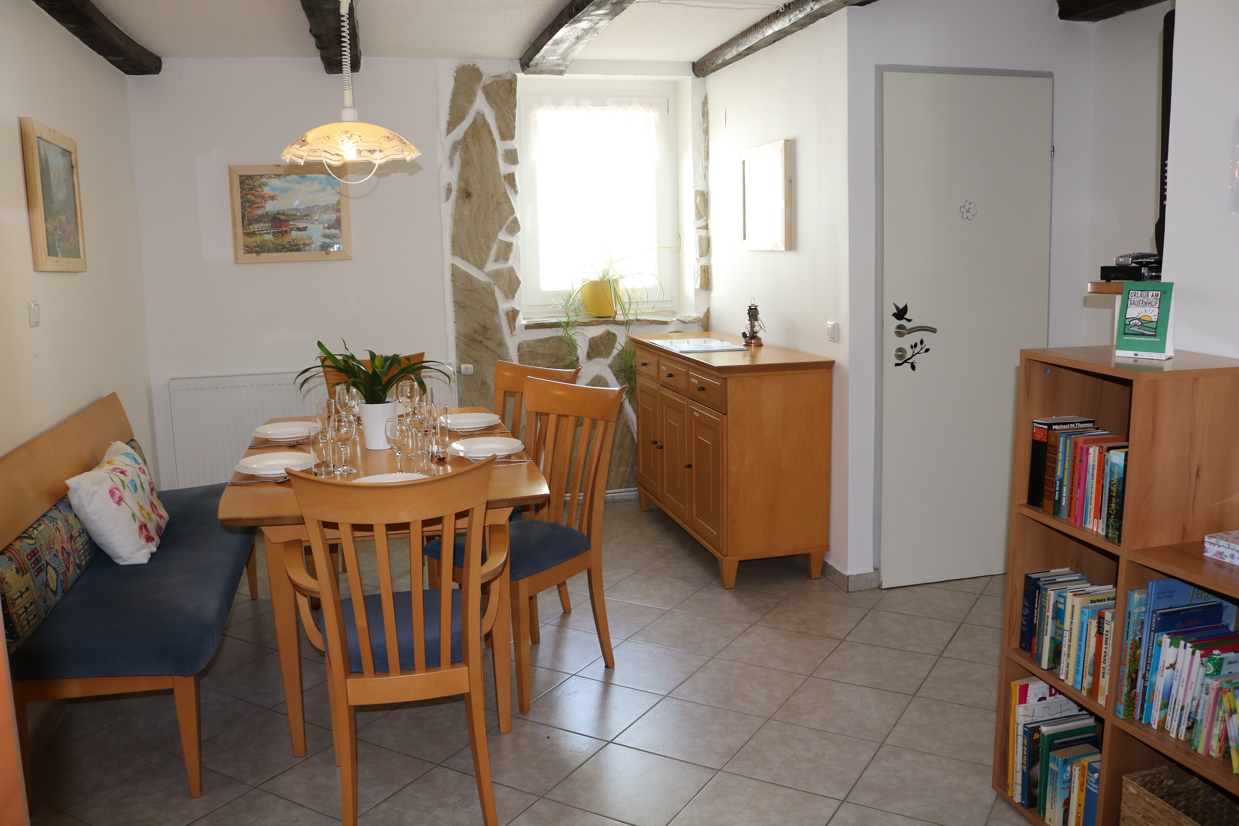 Essbereich mit Holztisch, Stühlen und Bücherregal.