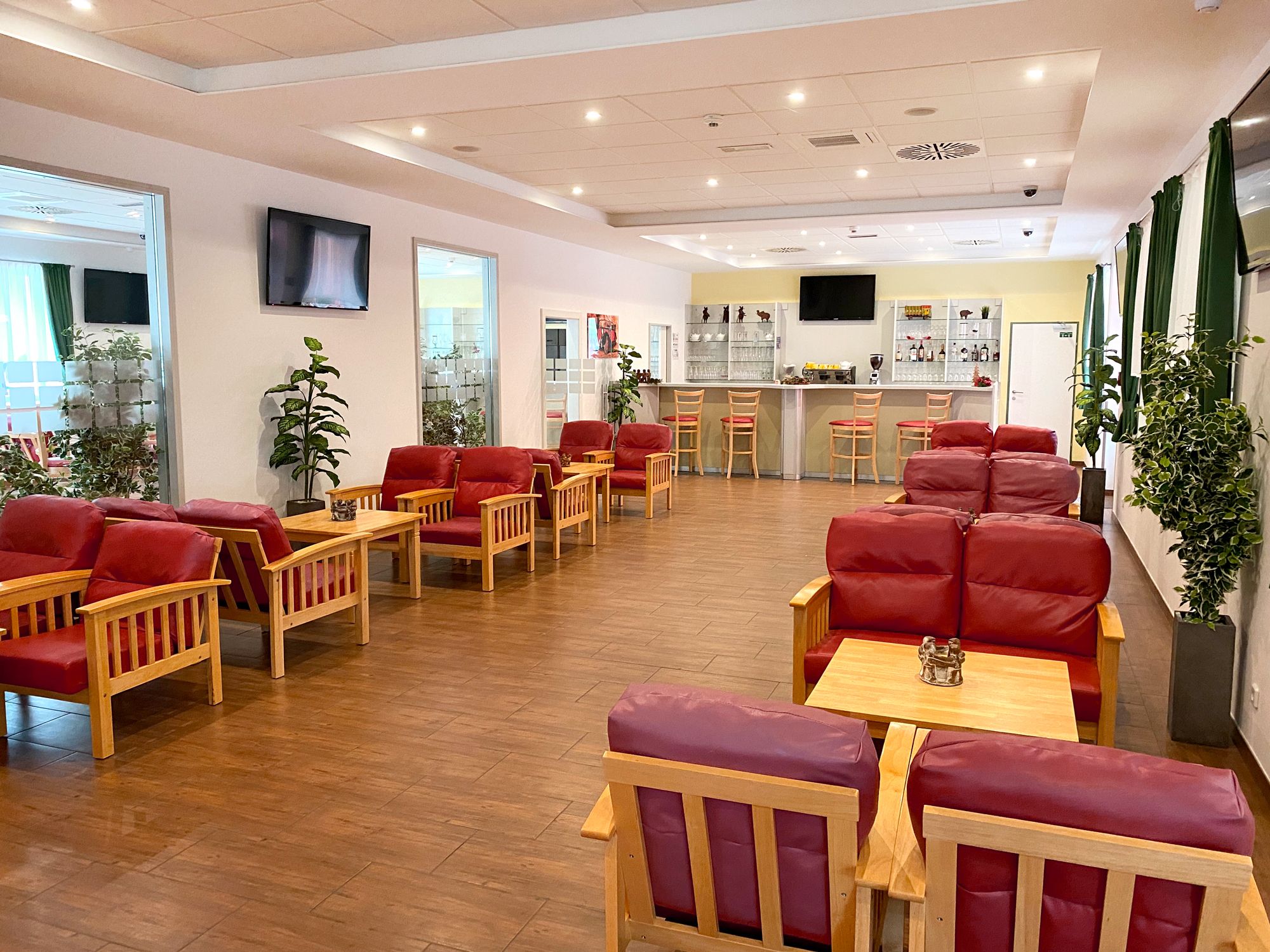 Helle Lounge mit Bar und roten, gepolsterten Sitzmöbeln und kleinen Tischen