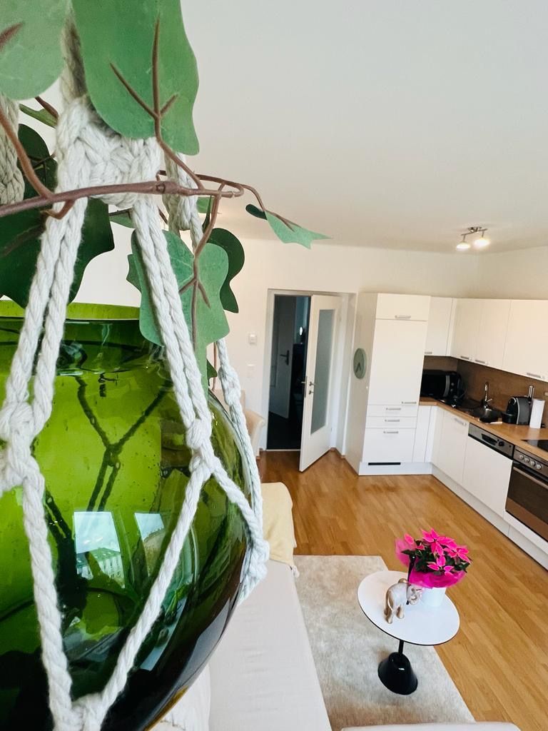 Moderne Küche in einer Ferienwohnung mit grüner Glasvase im Vordergrund.