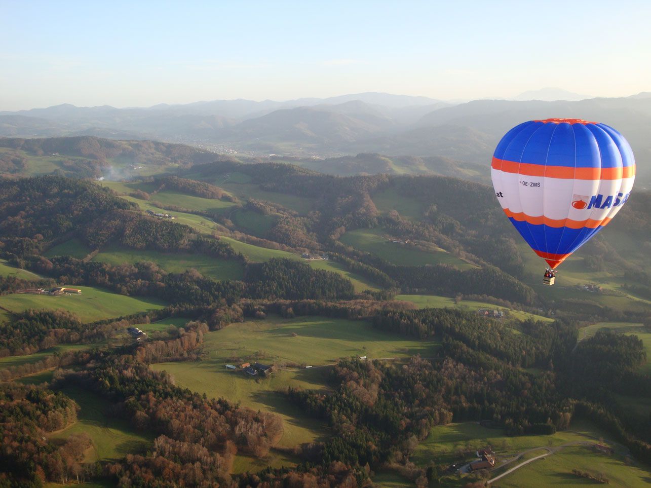 Heißluftballon über grüner Hügellandschaft im Traisental.