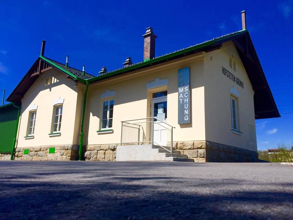 Außenansicht eines kleinen Museumsgebäudes mit gelber Fassade und grünen Akzenten.