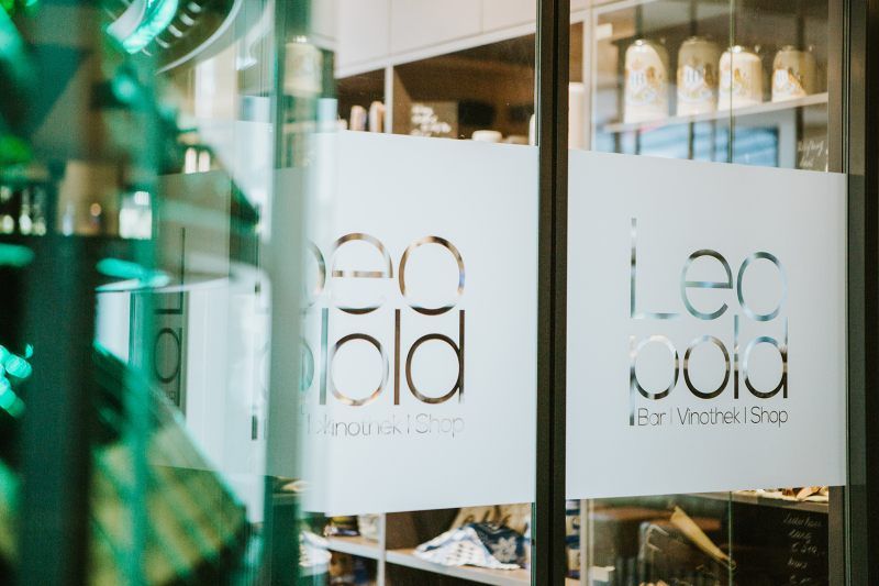 Eingang zur Vinothek mit dem Schriftzug 'Leopold Bar Vinothek Shop' auf der Glastür.