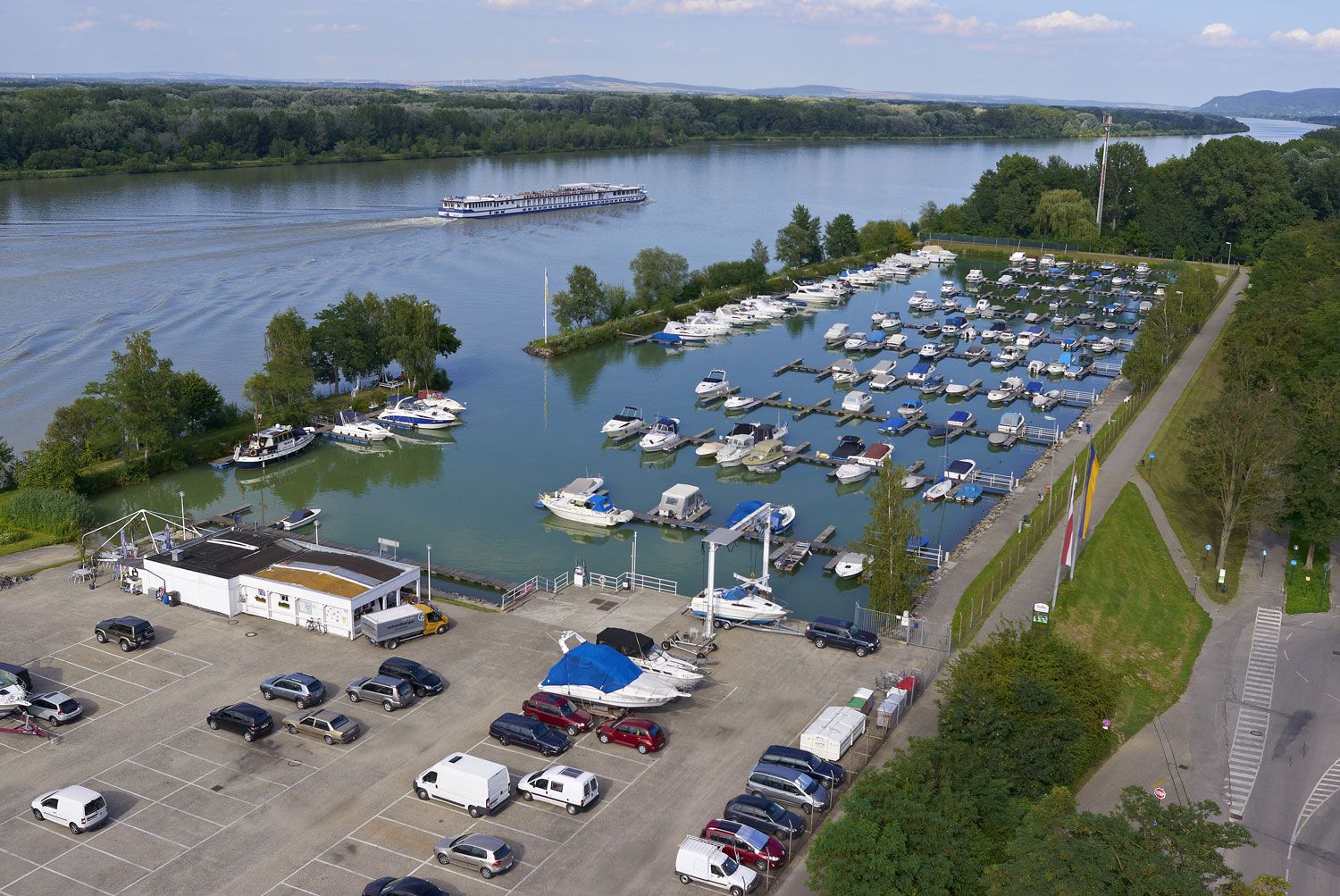 Luftaufnahme des Yachthafens Tulln mit vielen Booten und einem Fluss im Hintergrund.