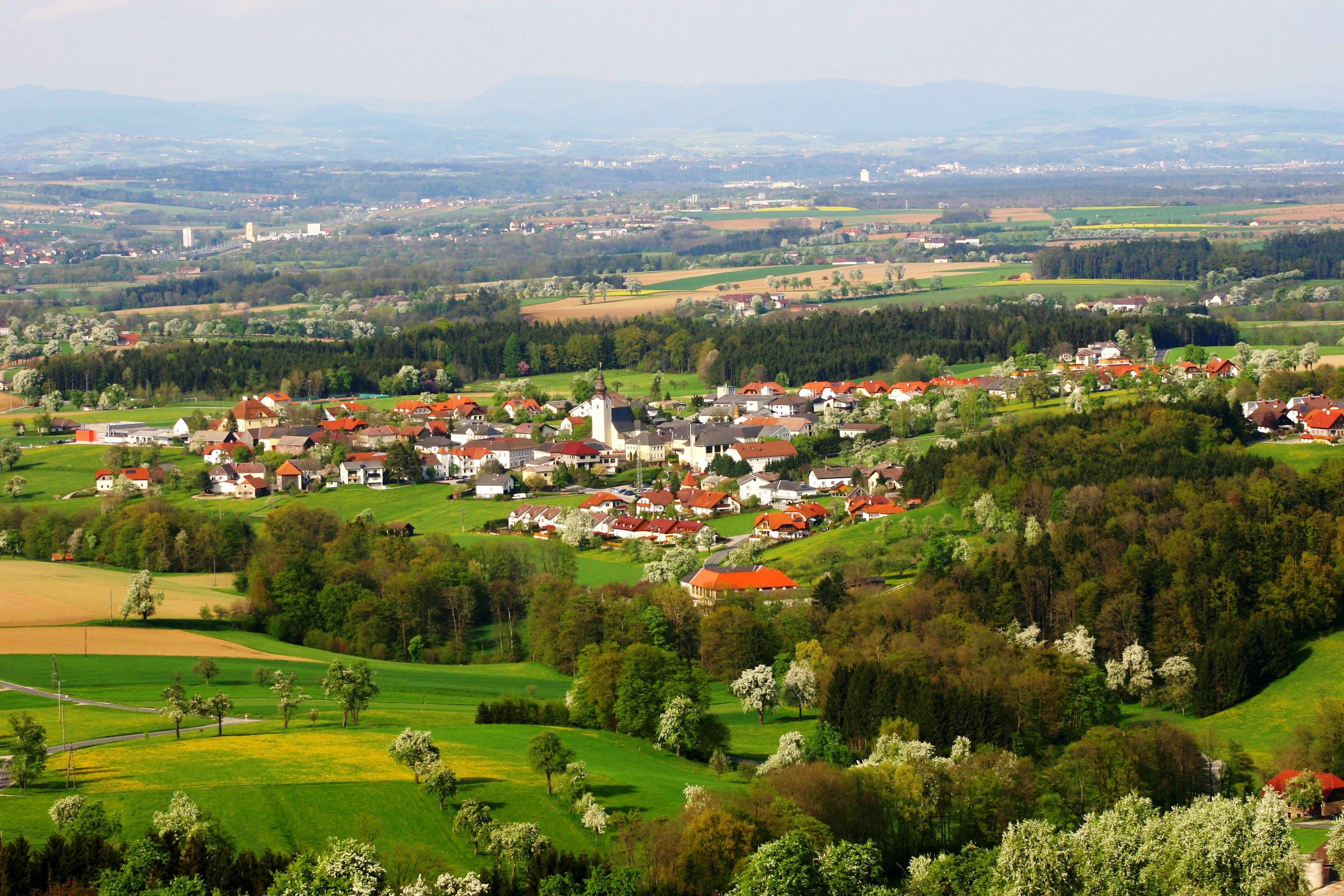 Luftaufnahme der Gemeinde Biberbach mit grünen Feldern und Wäldern.