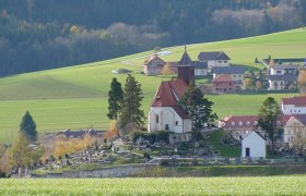 Erasmuskirche in Krumbach mit umliegendem Friedhof und gr&uuml;ner Landschaft.