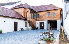 Innenhof eines Gästehauses mit Holzelementen und gepflastertem Boden.