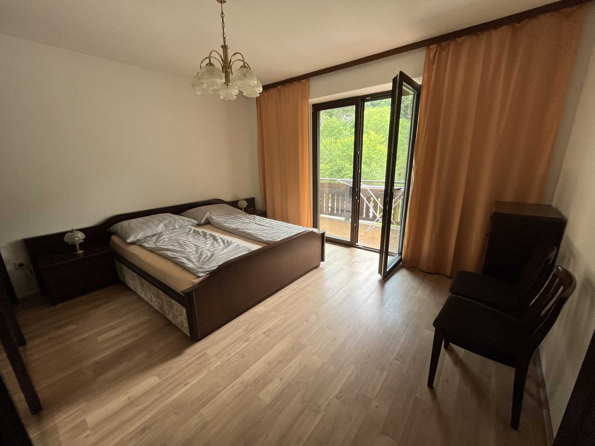 Schlafzimmer mit Doppelbett, Balkon und Vorhängen.