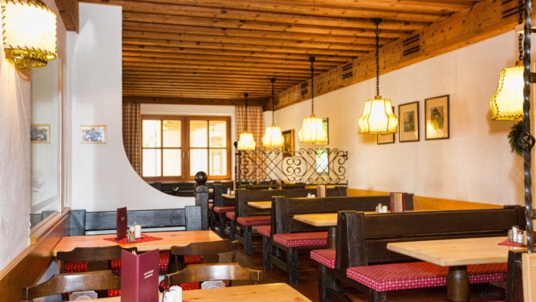 Gem&uuml;tlicher Innenraum eines traditionellen Heurigen mit Holzm&ouml;beln und karierten Sitzpolstern.